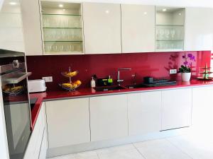 a kitchen with white cabinets and a red wall at Villa Sunkiss Algarve Carvoeiro in Carvoeiro