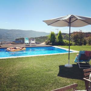 a person laying in a raft in a pool with an umbrella at Casas da Li in Arcos de Valdevez