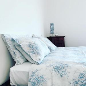 uma cama com lençóis e almofadas azuis e brancos em Rubino27 em Sordevolo