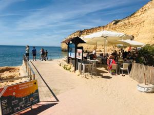 a beach with people sitting at tables and umbrellas at Villa Sunkiss Algarve Carvoeiro in Carvoeiro