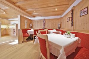 a restaurant with tables and red chairs and wooden walls at Garni Cristin & Dep Antina in Colfosco