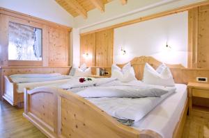 two beds in a large room with wooden walls at Garni Cristin & Dep Antina in Colfosco