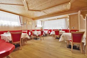 a restaurant with white tables and red chairs at Garni Cristin & Dep Antina in Colfosco +32 photos
