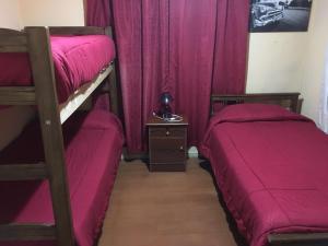 two bunk beds in a room with purple curtains at HOSTAL CAUQUENES in De Cauquenes
