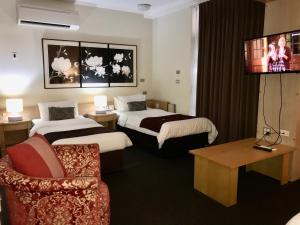 a hotel room with two beds and a chair at Mariners Court Hotel Sydney in Sydney