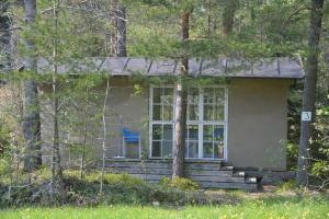 a small house in the woods with a blue chair at Sattmark EcoCabin in Pargas