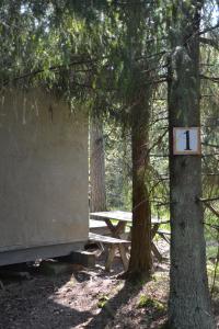 a picnic table in the woods with a sign on a tree at Sattmark EcoCabin in Pargas