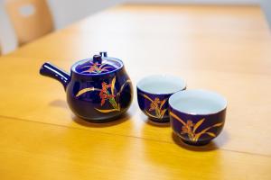 two cups and a teapot on a wooden table at Convertel Honhaneda by Tranova in Tokyo