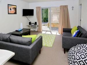 uma sala de estar com dois sofás e uma televisão em Harakeke House Downstairs - Ohakune Unit em Ohakune