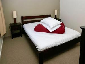 łóżko z białą i czerwoną pościelą oraz 2 szafkami nocnymi w obiekcie Harakeke House Downstairs - Ohakune Unit w mieście Ohakune