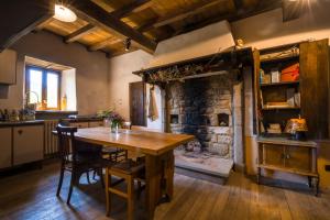 cocina con mesa de madera y chimenea de piedra en Ostello Podesteria di Gombola - arte e territorio, en Polinago