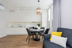 ein Wohnzimmer mit einem Tisch und Stühlen sowie eine Küche in der Unterkunft Yellow Rentyear Apartments in Danzig