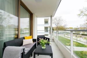 a balcony with a couch and a table with flowers on it at Yellow Rentyear Apartments in Gdańsk