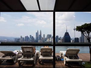 a group of chairs sitting on a deck with a view of the city at Regalia Residences KLCC Infinity Pool by 109 Suites in Kuala Lumpur