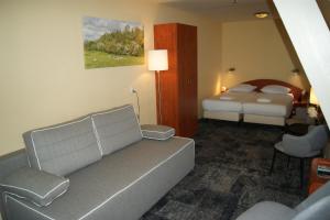 a hotel room with a bed, couch and a television at Fletcher Hotel Gilde in Deventer