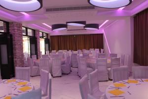 un salón de banquetes con mesas y sillas blancas e iluminación púrpura en Petsas Apartments, en Bahía de Coral