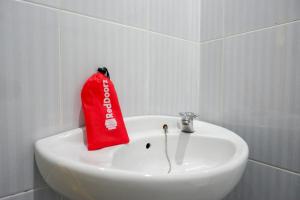 um saco vermelho sentado em cima de um lavatório branco em RedDoorz near Lippo Plaza Buton em Baubau