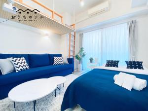 een slaapkamer met een blauw bed en een bank bij OUCHI HOTEL Otemachi in Hiroshima