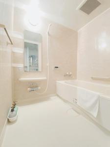 a white bathroom with a tub and a sink at OUCHI HOTEL Otemachi in Hiroshima