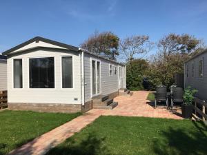 a small white house with a patio in a yard at Beach Chalet Tranquilo in Petten