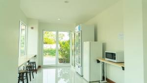 a kitchen with a refrigerator and a table with a microwave at The Willing Hotel and Residence in Lak Si