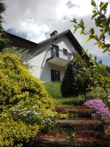 a white house with a balcony and some flowers at Apartament Leszczynowa 7 blisko Zatora in Spytkowice