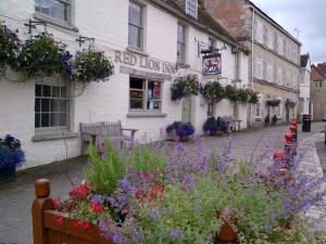 a building with a bunch of flowers in front of it at THE RED LION in Cricklade