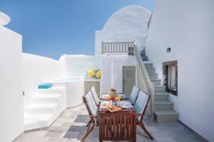 a table in a room with white walls and stairs at Santorini 180 Degrees in Pyrgos