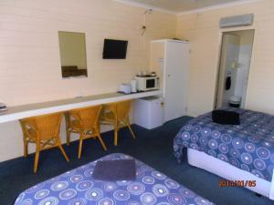 a room with two beds and a desk and a kitchen at Opal Motel in Leongatha
