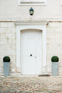 białe drzwi garażowe na budynku z białej cegły z dwoma w obiekcie Maison Ailleurs w mieście Chartres