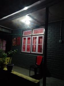 una silla roja sentada fuera de un edificio por la noche en Vamoose Tragopan, en Aritar