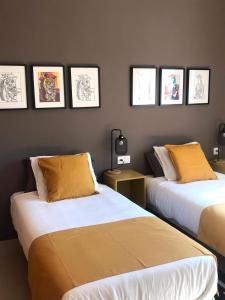 2 camas en una habitación con fotos en la pared en Apartamentos Élite - Art Collection - Pablo, en Mérida