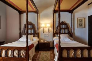 a bedroom with two four poster beds in a room at Parador de Ubeda in Úbeda