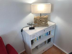 a lamp on top of a white cabinet with books at Auszeit in Beckerwitz