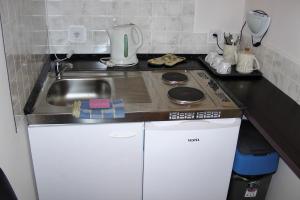 a kitchen with a stove top oven and a sink at Green Lake Park Apartments in Vecsés