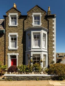 een groot bakstenen huis met een rode deur bij Dorchester House in Keswick