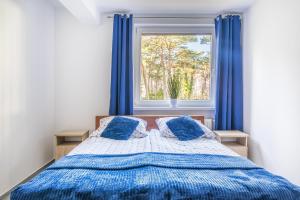 a bedroom with a bed with blue curtains and a window at Apartament Dominika in Jurata