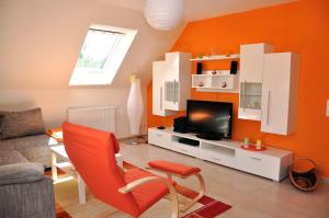 uma sala de estar com uma parede laranja e uma televisão em Ferienhaus Müritzsonne / OG-Appartement em Marienfelde