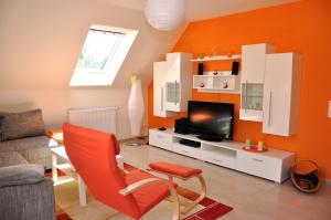 a living room with an orange wall and a tv at Ferienhaus Müritzsonne / OG-Appartement in Marienfelde