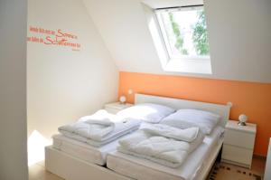 1 dormitorio con 2 camas con almohadas blancas y ventana en Ferienhaus Müritzsonne / OG-Appartement en Marienfelde