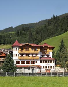 a large white building with balconies on a hill at Alpenherz Hotel Garni in Gerlos