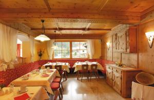 a dining room with tables and red chairs at Alpenherz Hotel Garni in Gerlos