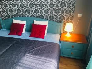 a blue bed with two red pillows and a lamp at Apartamenty Rodzinne Krokowa in Krokowa