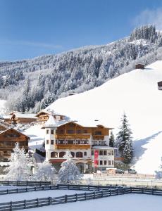 a hotel in the snow in front of a mountain at Alpenherz Hotel Garni in Gerlos