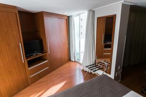 um quarto com uma cama, uma televisão e uma porta em Hotel Boulevard em Londrina