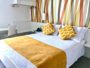 a bedroom with a bed with yellow and white pillows at Hotel 3K Faro Aeroporto in Faro +27 photos