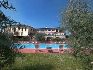 una piscina con sillas y un edificio de fondo en Splendid holiday home in Soiano del lago with furnished patio, en Soiano del Lago