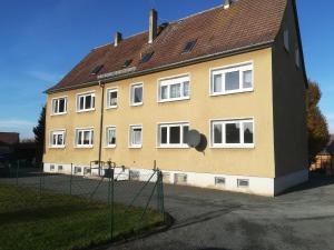 a yellow building with white windows and a fence at Ländliche Erholung 3 in Heideland