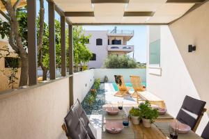 un patio al aire libre con mesas y sillas en el balcón en Villa Amelia, en Kalathas