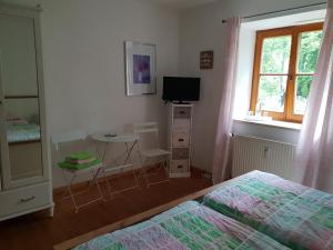 a bedroom with two beds and a table and a television at Martina's Place Bed & Breakfast in Rottenbuch